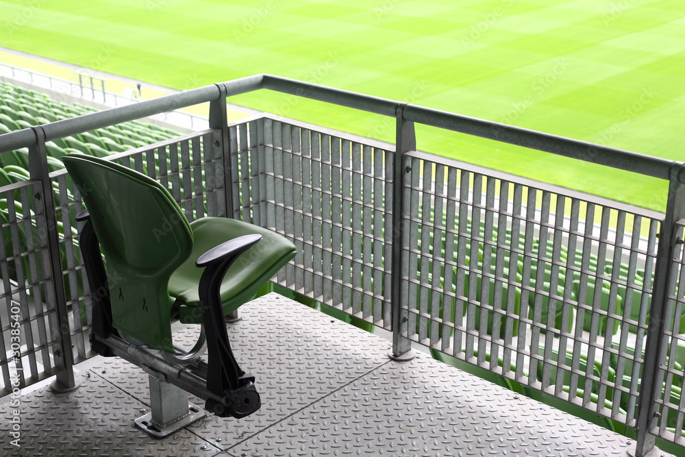 Obraz premium One green plastic fold-flat seat on tribune of large stadium