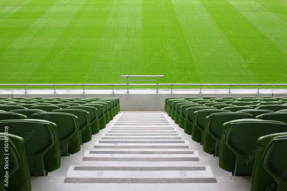 Naklejka premium Rows of folded, green, plastic seats in very big, empty stadium