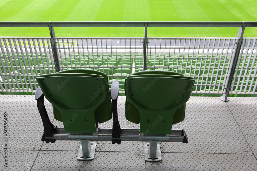 Fototapeta premium Two green plastic seats on tribune of large stadium