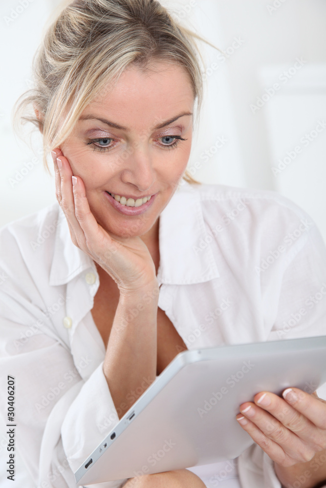 Blond woman using electronic tablet at home Blond woman using electronic tablet at home