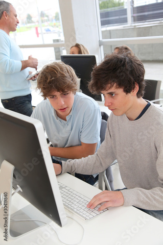 Teenagers in classroom working on desktop computer