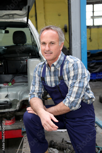 Portrait of garage owner standing by vehicle