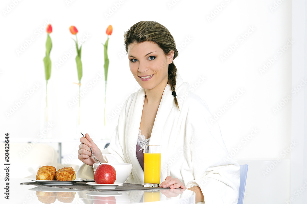 beautiful woman in bathrobe is having breakfast