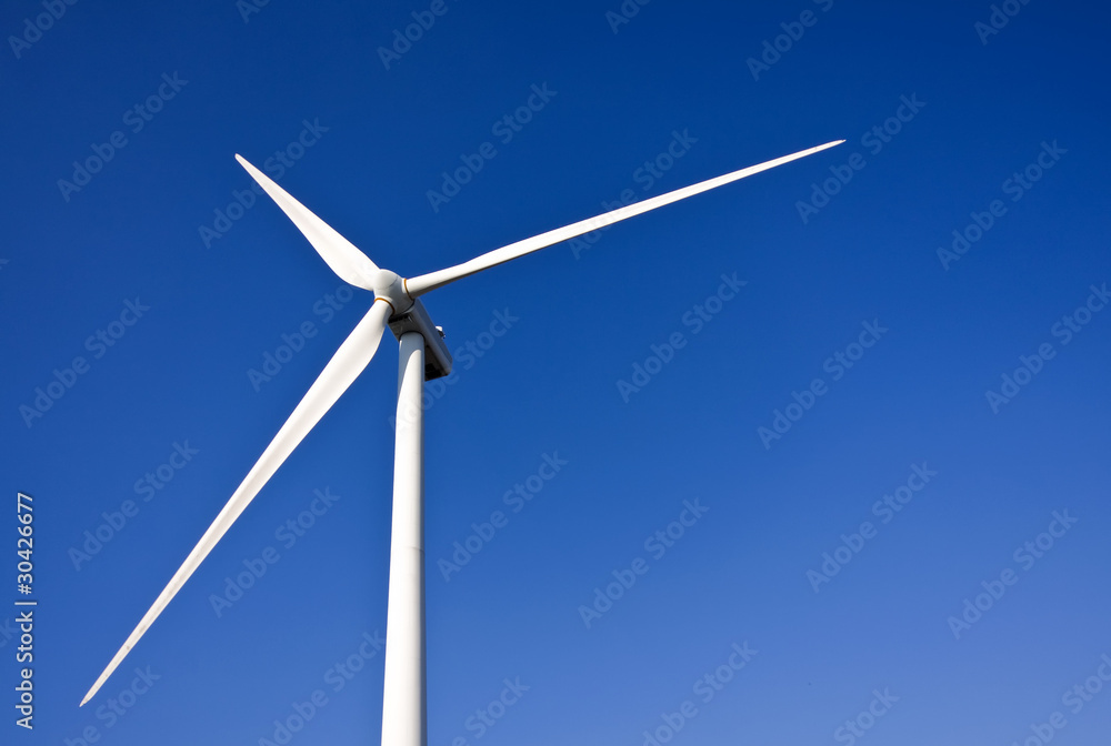 White wind turbine generating electricity on blue sky White wind turbine generating electricity on blue sky