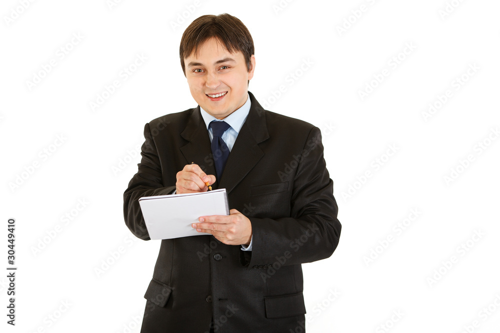 Smiling modern businessman making notes in notebook Smiling modern businessman making notes in notebook