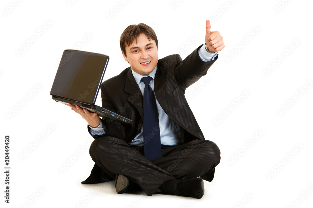 Businessman sitting on floor with laptop showing thumbs up Businessman sitting on floor with laptop showing thumbs up