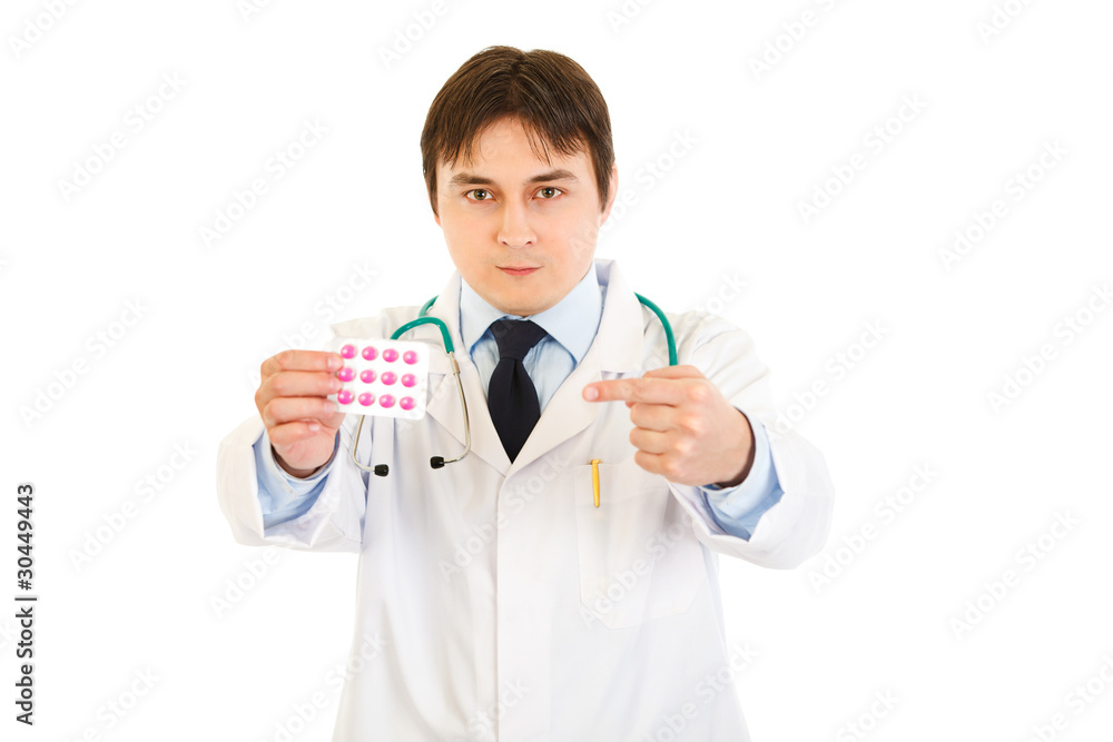 Serious medical doctor pointing finger at pack of pills Serious medical doctor pointing finger at pack of pills