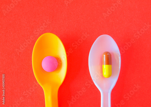 Spoonful of Pills to Keep Healthy Concept Image on red backgroun