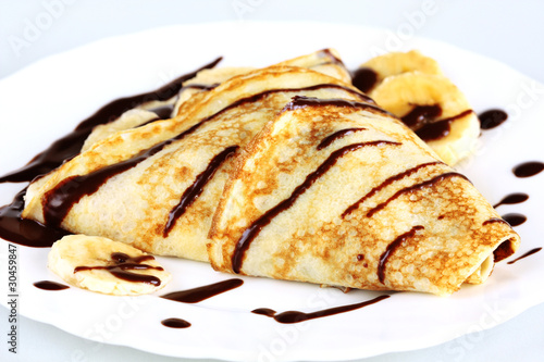 close-up pancakes with bananas and chocolate on white plate