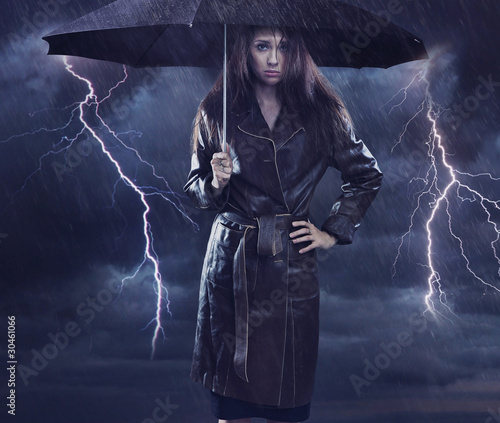 Single woman wearing coat holding umbrella. Creative szmbol of t photo