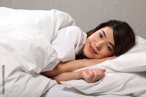 Beautiful young woman lying in bed smiling
