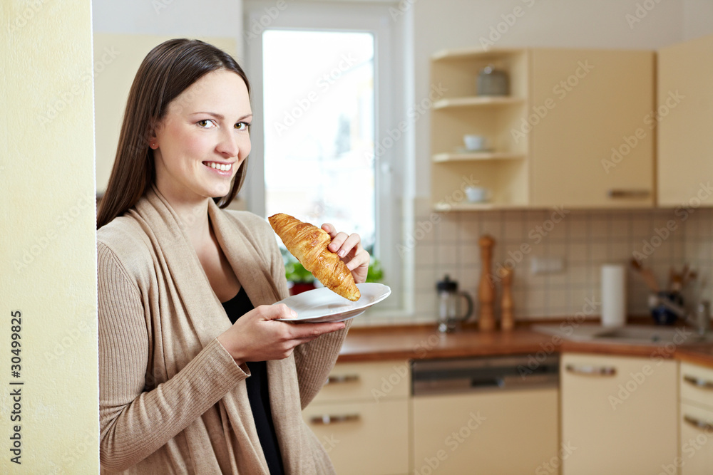 Frau mit Croissant in Küche