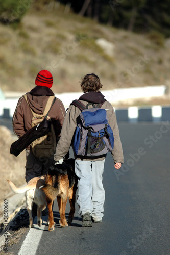 Hombres con sus perros caminando por la carretera