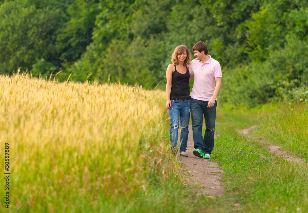 Young couple walking on the road in a field of wheat