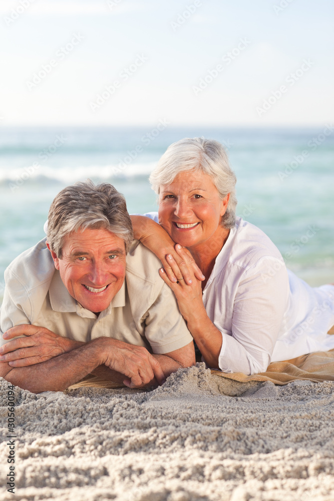 Elderly couple lying down on the beach Elderly couple lying down on the beach