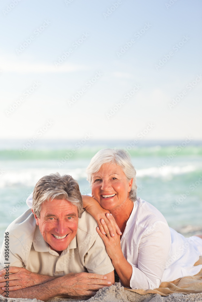 Elderly couple lying down on the beach