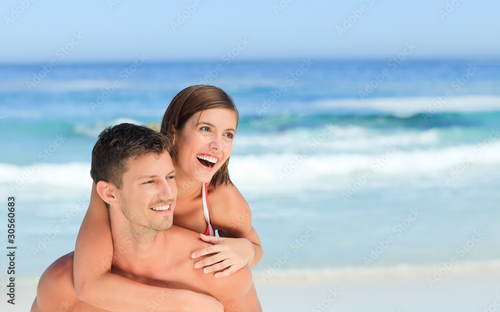 Man having wife a piggyback on the beach Man having wife a piggyback on the beach