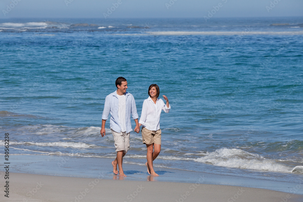 © WavebreakMediaMicro - Couple walking on the beach under the sun