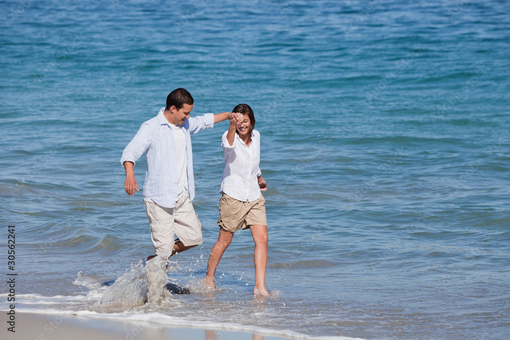 Couple walking on the beach under the sun Couple walking on the beach under the sun