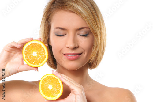Portrait of a young woman playing with fresh and tasty orange