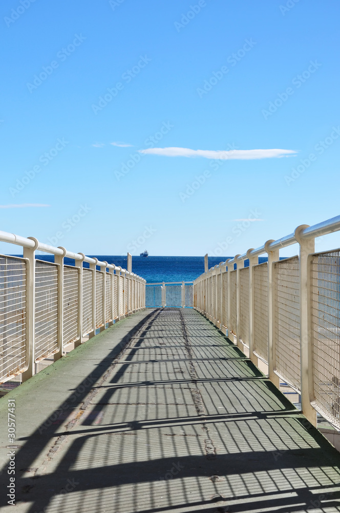 Iron pier to coast of Alicante with cargo ship, Spain