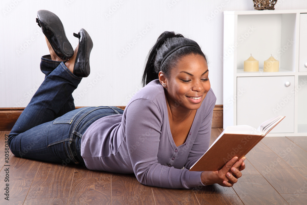 Beautiful girl lying on the floor reading a book Stock Photo
