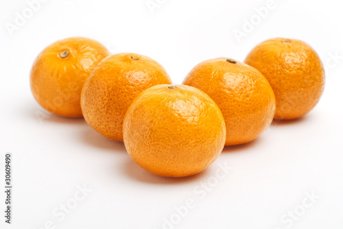 Tangerine in front with blurred row of mandarins on white