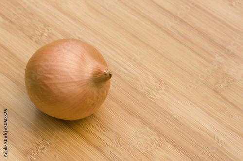 Single brown onion on wooden table  space for text