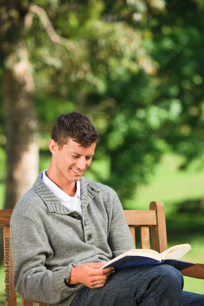 Young man reading his book on the bench Young man reading his book on the bench