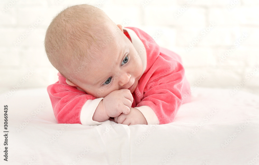 baby in is bright-pink overalls lies on a stomach baby in is bright-pink overalls lies on a stomach