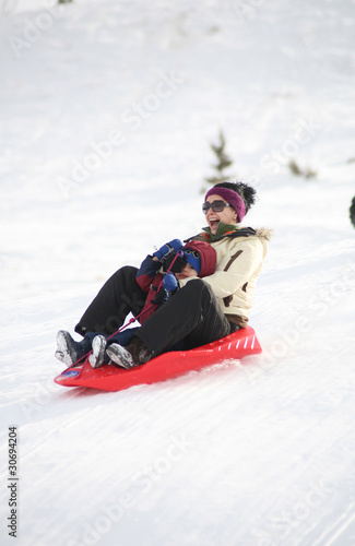 family sledding during winter down a hill