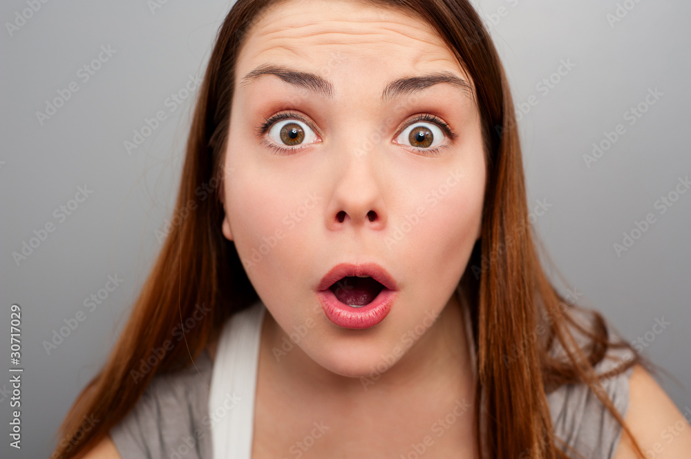 amazed young woman over grey background amazed young woman over grey background