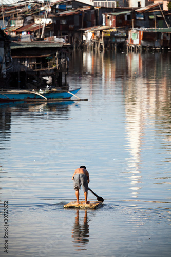 Man on raft in Philippines - squatter shanty area