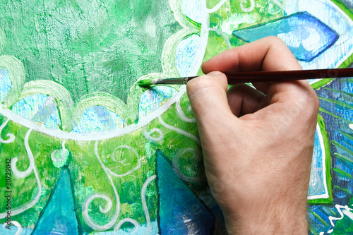 closeup of man painting green picture with circle pattern, manda