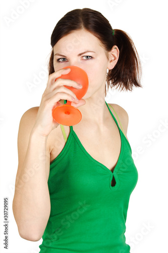 young girl in green shirt drinking from orange glass  isolated