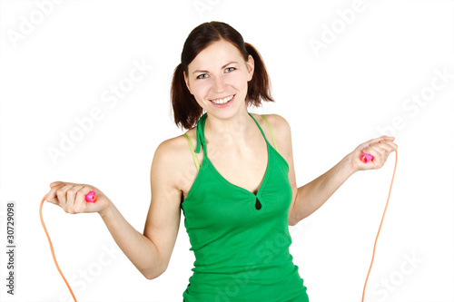 young girl in green shirt with skipping rope, smiling and lookin