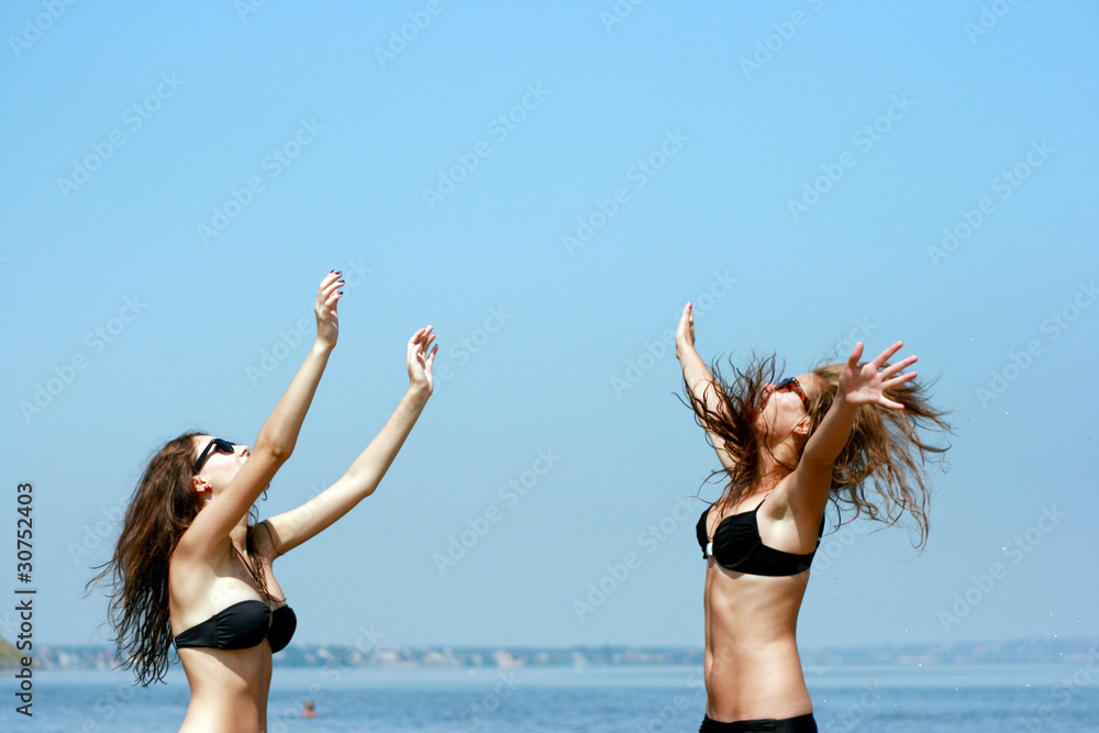 Naklejka premium Happy young women playing ball at the beach