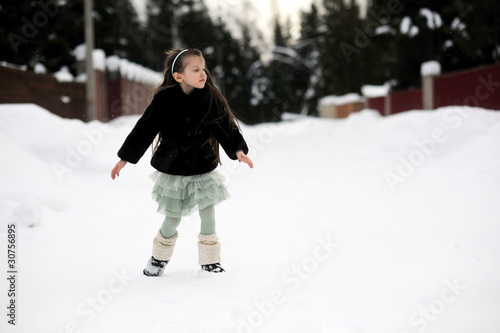 Adorable little girl in green tutu dances outside in snow