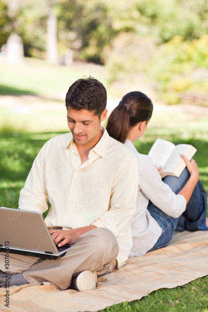 Man working on his laptop while his wife is reading Man working on his laptop while his wife is reading