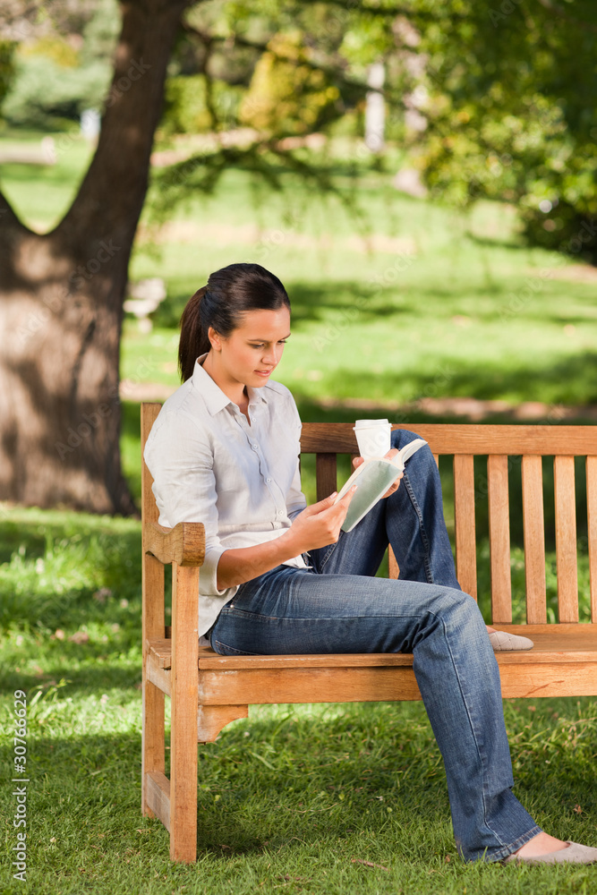 Obraz premium Young woman reading on the bench