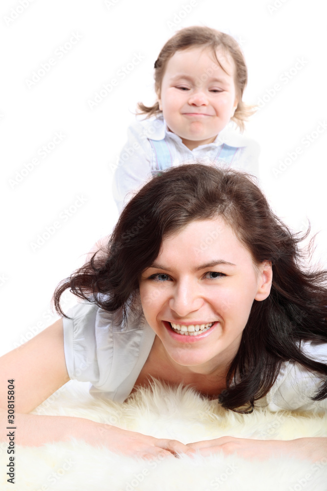 Funny little girl sits on mother which lying on white fluffy fur Funny little girl sits on mother which lying on white fluffy fur
