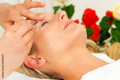 Frau im Kosmetikstudio bekommt die Augenbrauen gezupft photo