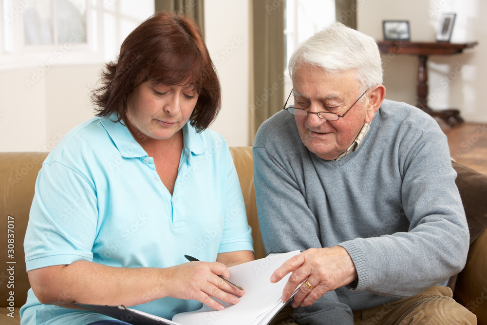 Senior Man In Discussion With Health Visitor At Home