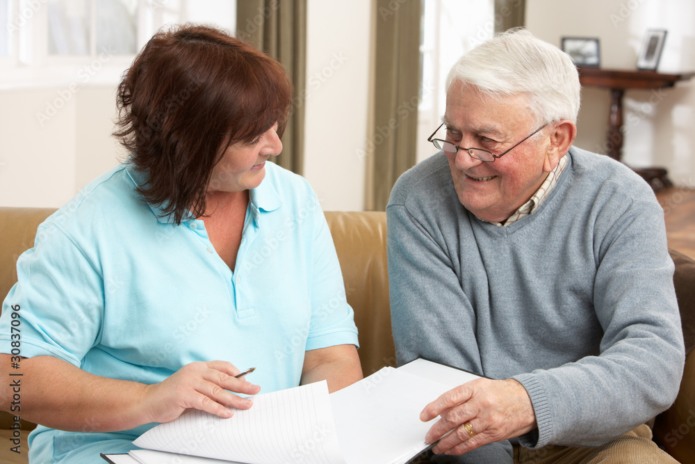 Senior Man In Discussion With Health Visitor At Home