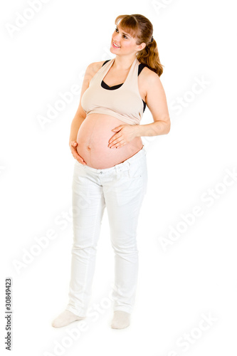 Dreaming beautiful pregnant woman holding her belly isolated