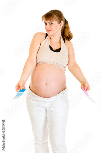 Confused pregnant woman holding color paint samples