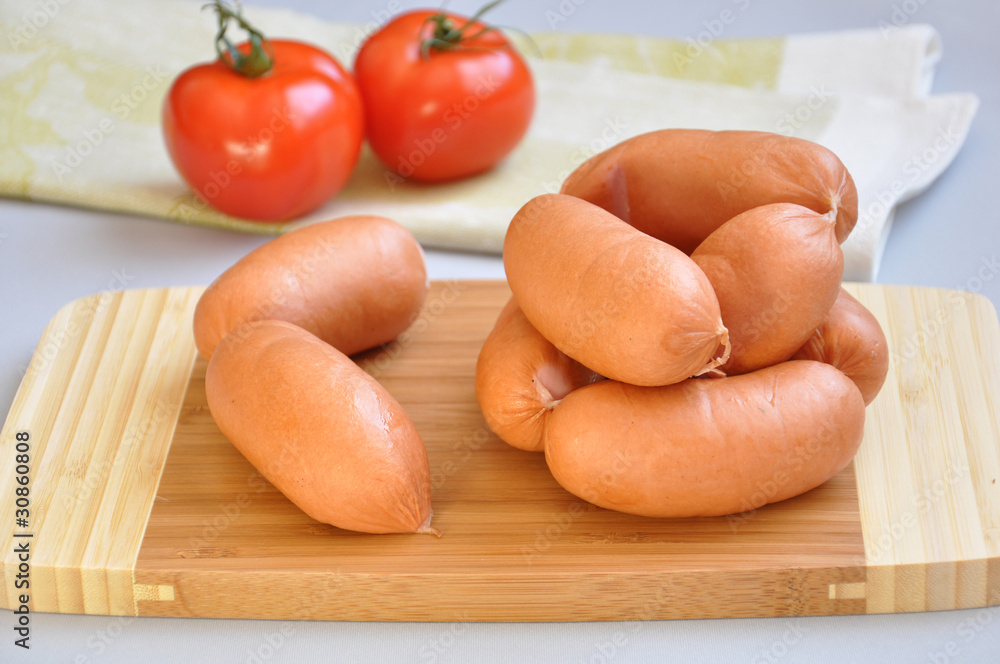 Delicious sausages on a cutting board and ripe tomatoes Delicious sausages on a cutting board and ripe tomatoes