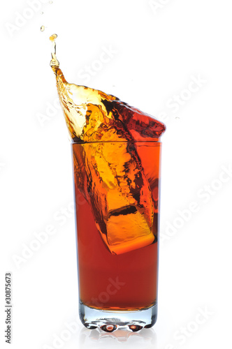 Ice falling in glass with black tea