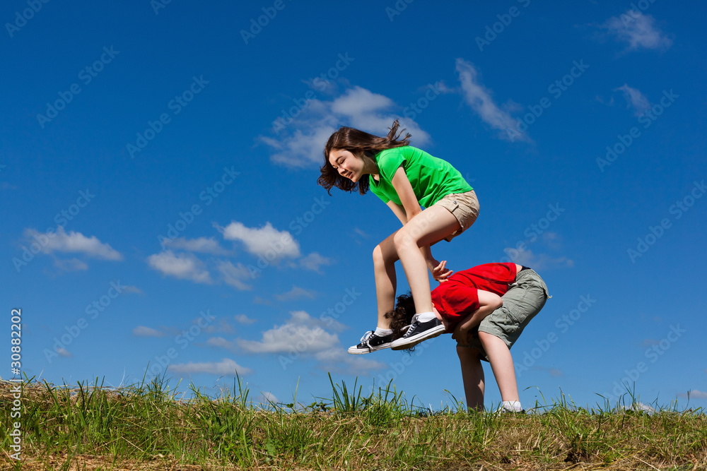 Girl and boy jumping, running against blue sky Girl and boy jumping, running against blue sky