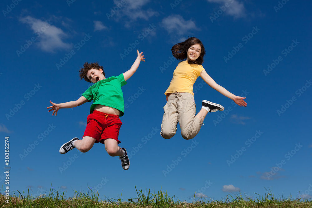 Girl and boy jumping, running against blue sky Girl and boy jumping, running against blue sky